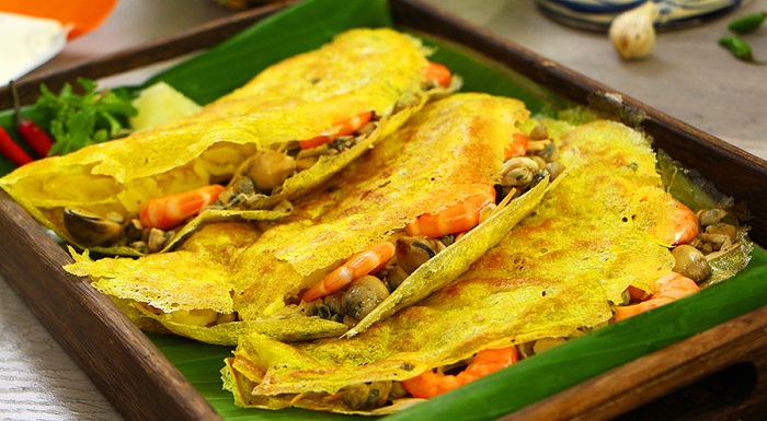 The filling usually includes shrimp, meat, and bean sprouts, served with raw vegetables and dipping sauce