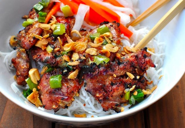 Grilled meat served with noodles, vegetables, and spicy dipping sauce, characteristic of this dish